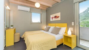 Ein Schlafzimmer mit Bett, Nachttischen, einem Fenster und Blick ins Grüne.