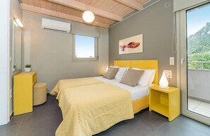 Ein Schlafzimmer mit Bett, Nachttischen, einem Fenster und Blick ins Grüne.