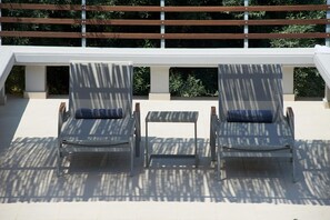 Two lounge chairs with blue cushions, a small table, and a white balustrade with greenery in the background. - Villa Porphyra - Four Bedroom Villa, Sleeps 8 (Lefkada City)