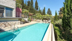 Ein Schwimmbecken mit einer Steinmauer und einem roten Gebäude im Hintergrund.