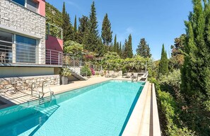 Ein Schwimmbecken mit einer Steinmauer und einem roten Gebäude im Hintergrund.