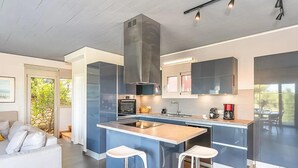 Eine moderne Küche mit Kochinsel, integrierten Geräten und einem Essbereich mit Sofa und Stühlen.