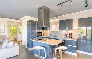 Eine moderne Küche mit Kochinsel, integrierten Geräten und einem Essbereich mit Sofa und Stühlen.