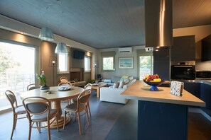 Cocina moderna con una isla central, comedor con sillas y un sofá.