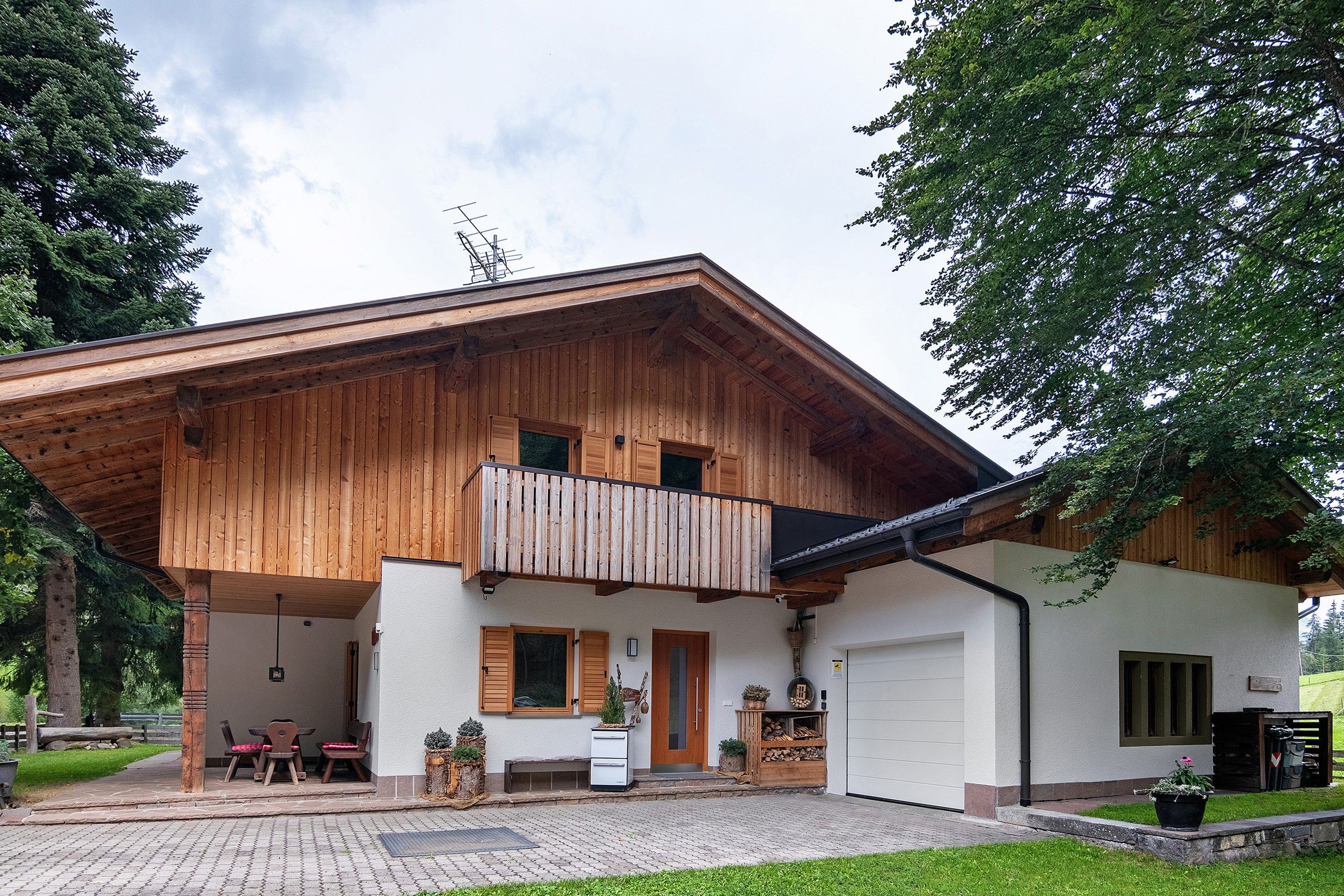 A two-story wooden house with a balcony, a covered patio, and a garage.