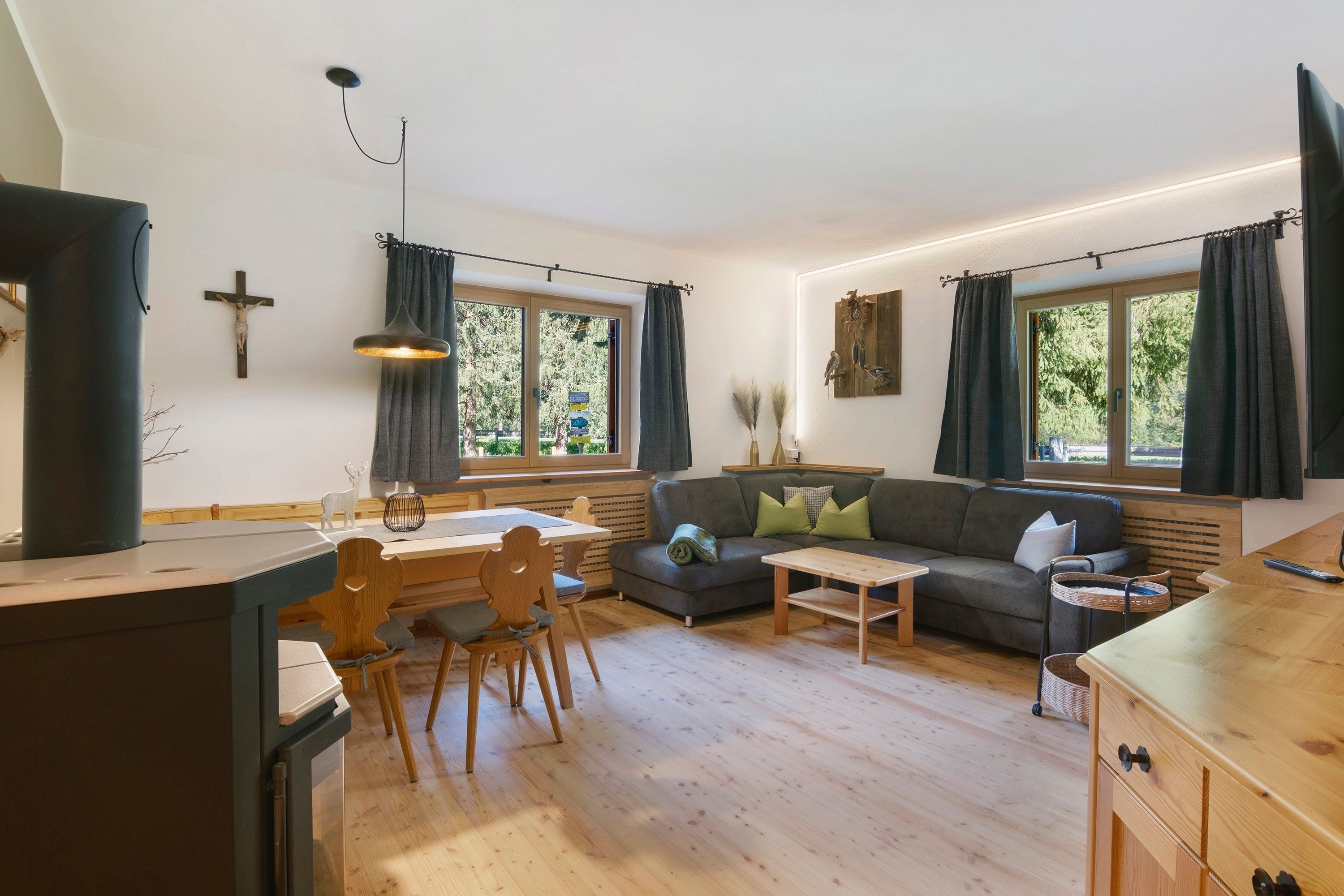 Un salon moderne avec une table à manger en bois, un canapé et un coin cuisine équipé d’une cuisinière.