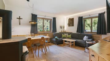 Un salon moderne avec une table à manger en bois, un canapé et un coin cuisine équipé d’une cuisinière.
