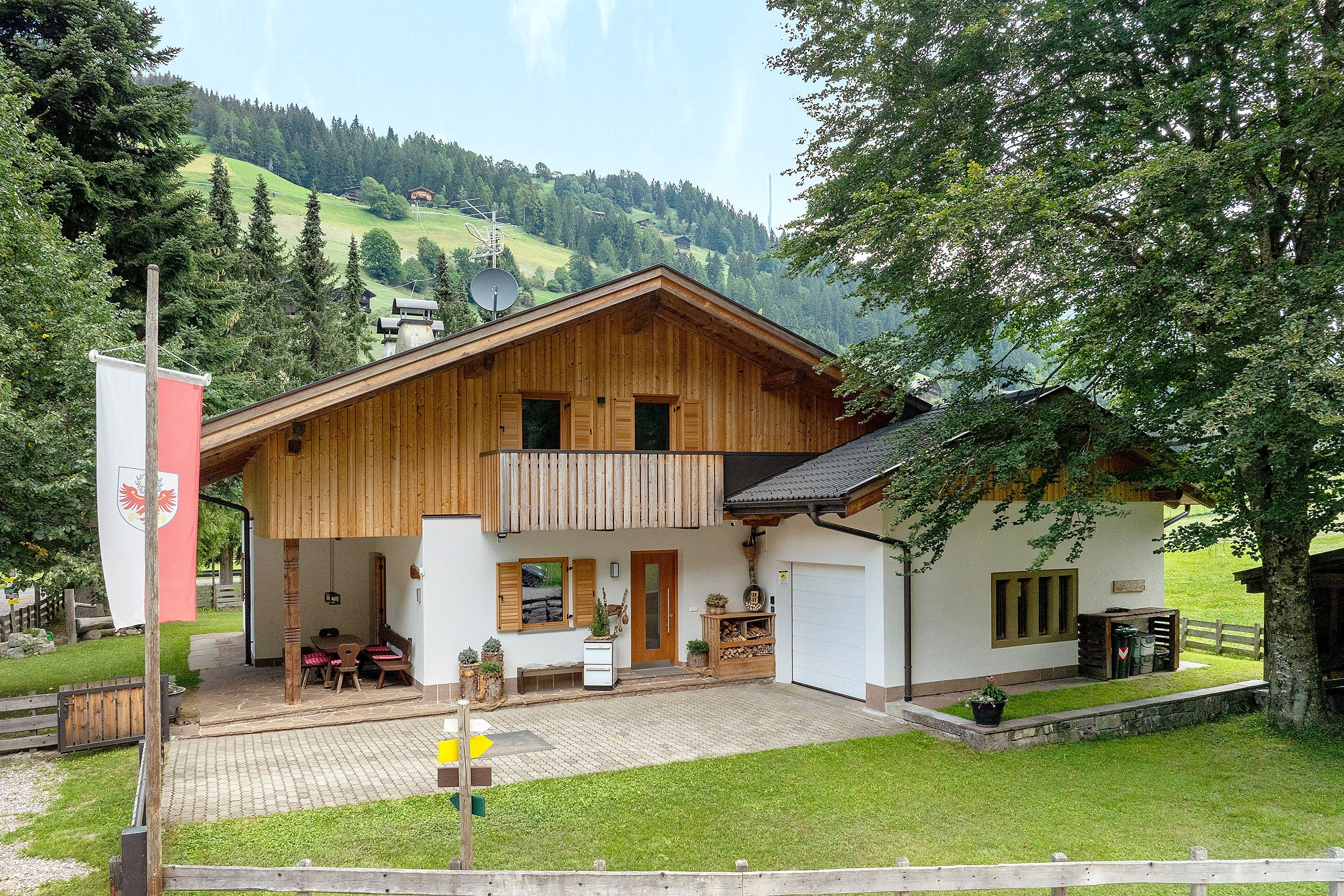 Una chalet in legno con balcone, zona pranzo e garage.