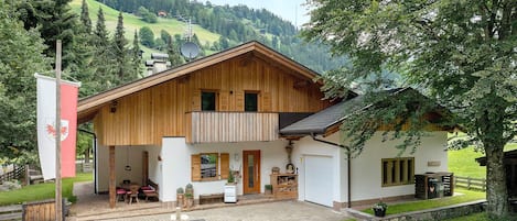 A wooden chalet with a balcony, a dining area, and a garage.