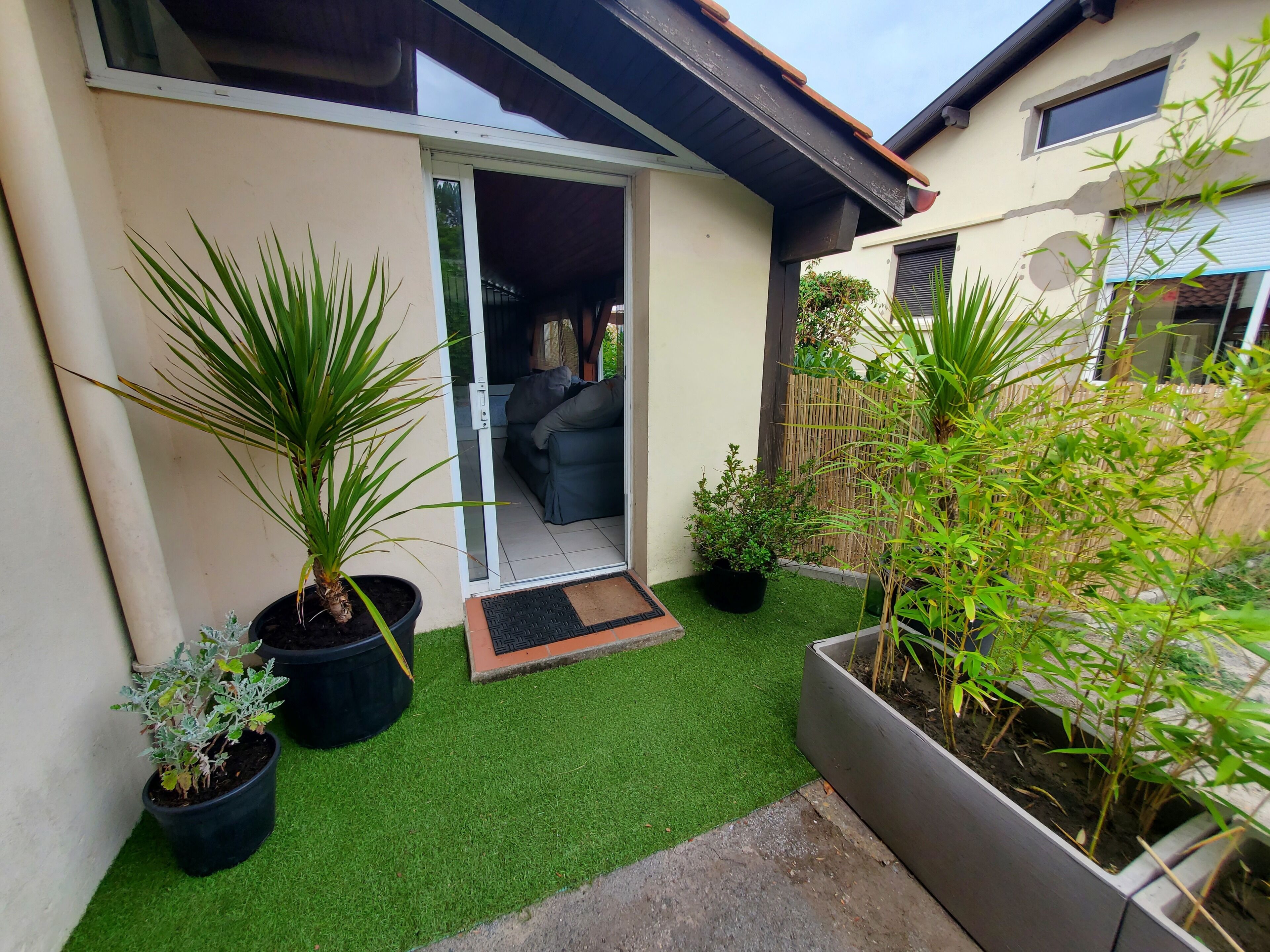 Una propiedad residencial con patio, plantas en macetas y puerta corrediza de vidrio que da a un espacio interior.