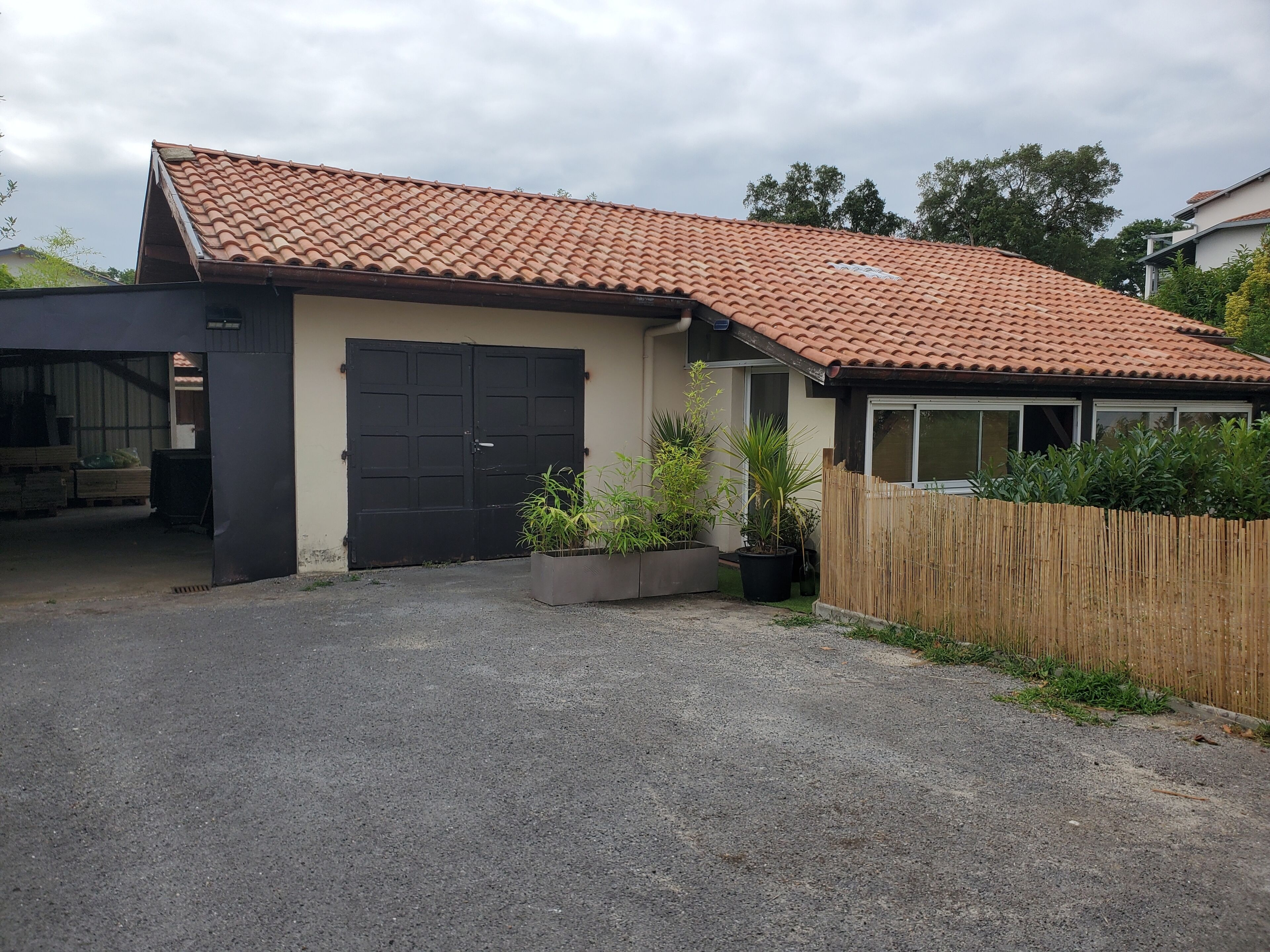 A residential building with a tiled roof, a garage, and a fenced yard.