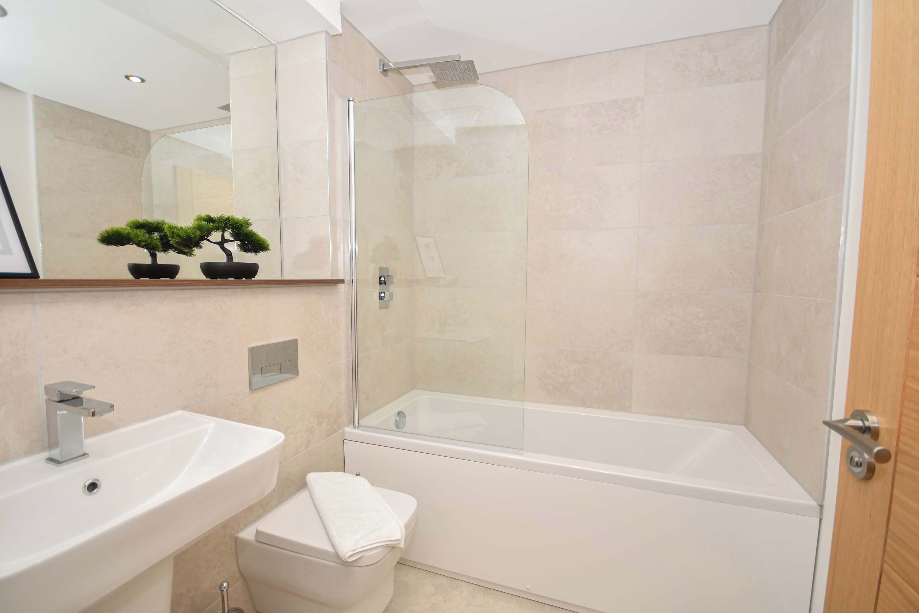 A modern bathroom with a glass-enclosed shower, a white sink, and a toilet.