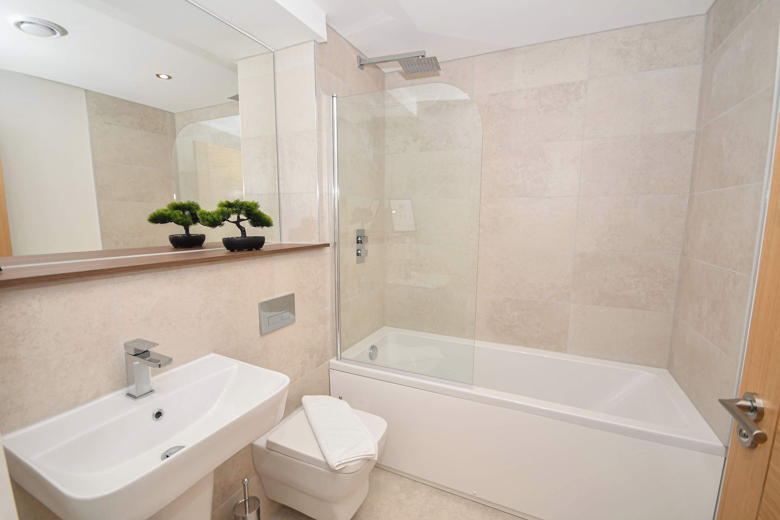 A modern bathroom with a glass shower enclosure, a white sink, and a toilet.