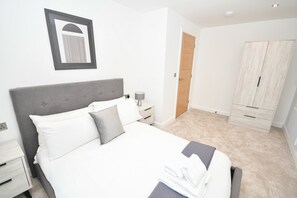 A bedroom with a bed, bedside tables, a lamp, a wardrobe, and a framed picture on the wall. - Bright and Spacious 1 Bed Apartment in Leeds (Leeds)