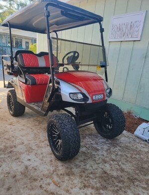 A red and white golf cart parked on a concrete surface.