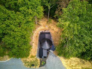 A single-story house with a sloped roof, surrounded by dense forest.