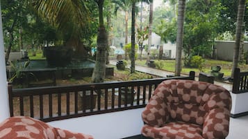 Un balcon donnant sur un jardin, une chaise à motifs et une table.