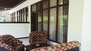 A room with a sofa and chairs, a small table, and large windows with curtains.