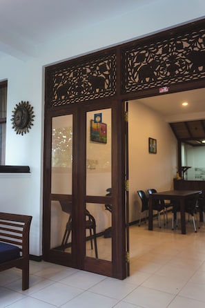 Una habitación con un separador de madera, una mesa de comedor, sillas y una zona de cocina al fondo.