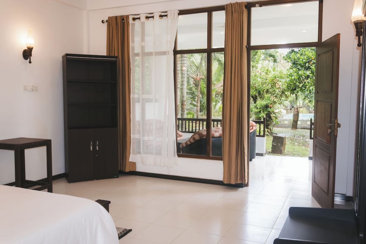 Un dormitorio con cama, armario, ventana con cortinas y vistas al exterior.