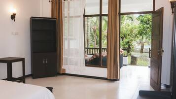 A bedroom with a bed, a wardrobe, a window with curtains, and a view of the outdoors.