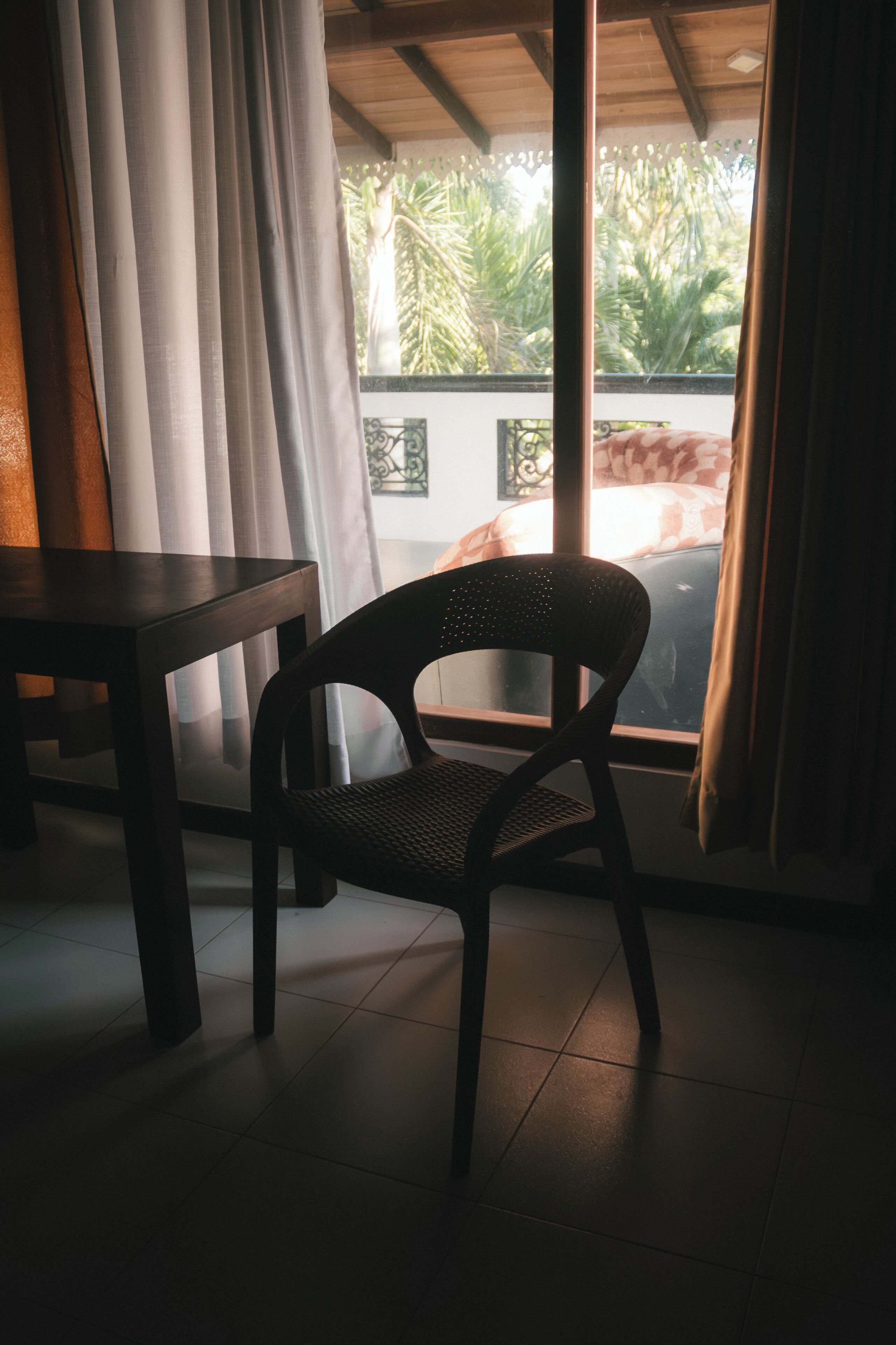 Una habitación con una silla cerca de una ventana, una mesa y vistas a zonas verdes al exterior.