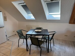 A dining area with a table and chairs, a ceiling with skylights, and a radiator.