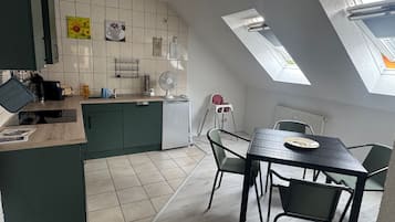 Eine moderne Küche mit Essbereich, gekennzeichnet durch eine hohe Decke mit Dachfenstern, einem eingebauten Geschirrspüler und einem kleinen Kühlschrank.