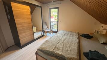 A bedroom with a bed, a chair, a wooden ceiling, and a sliding door.