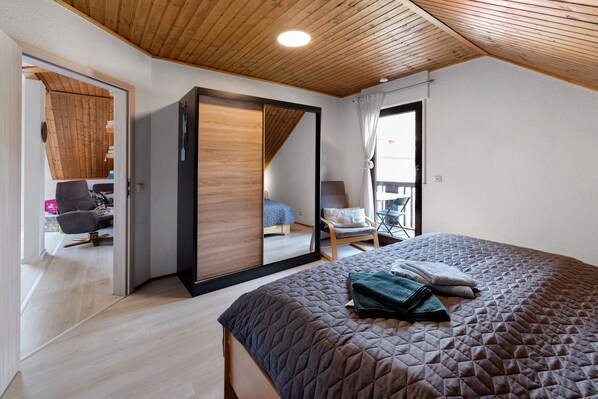 Un dormitorio con una cama grande, un armario de madera, una silla y un escritorio.