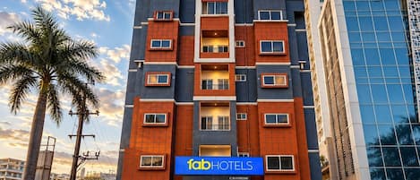 Un hotel de varios pisos con fachada moderna, que presenta un letrero llamativo que dice 'fabHOTELS HOTEL & CHECK IN'.