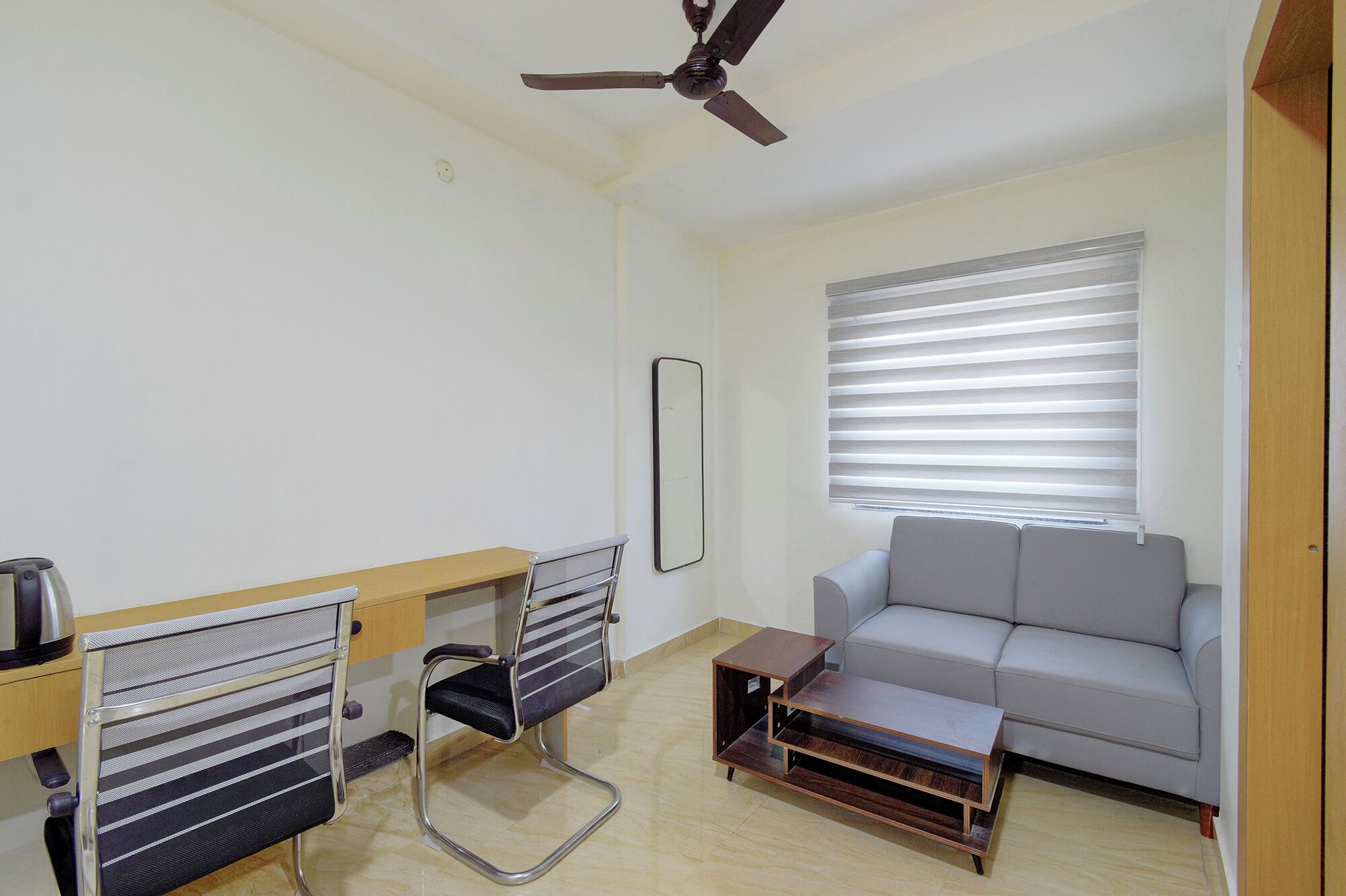 A room with a ceiling fan, a sofa, a small table, and a chair.