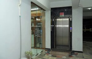 An elevator with a digital display, a glass door, and a tiled floor.