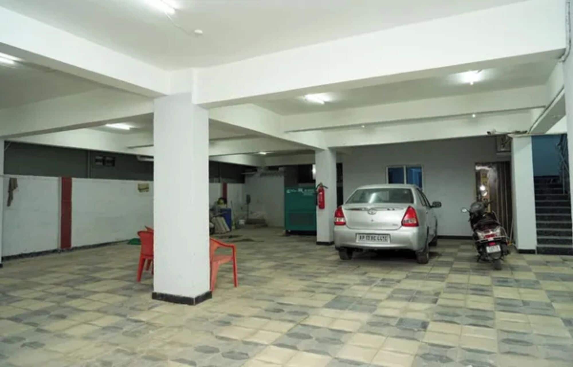 Un aparcamiento con un coche y una motocicleta, pilares blancos y suelo de baldosas.
