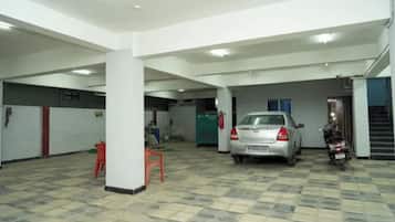 Un aparcamiento con un coche y una motocicleta, pilares blancos y suelo de baldosas.