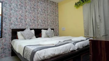 Una cama bien hecha con almohadas y una manta, un cabecero con estampado floral y un aparador de madera.