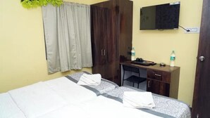 A hotel room with a bed, a desk, a wardrobe, a television, and a window with curtains.