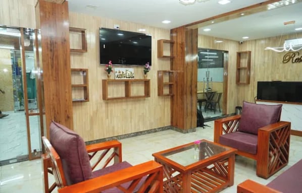 A hotel lobby with wooden paneling, a flat-screen TV, and a reception desk.