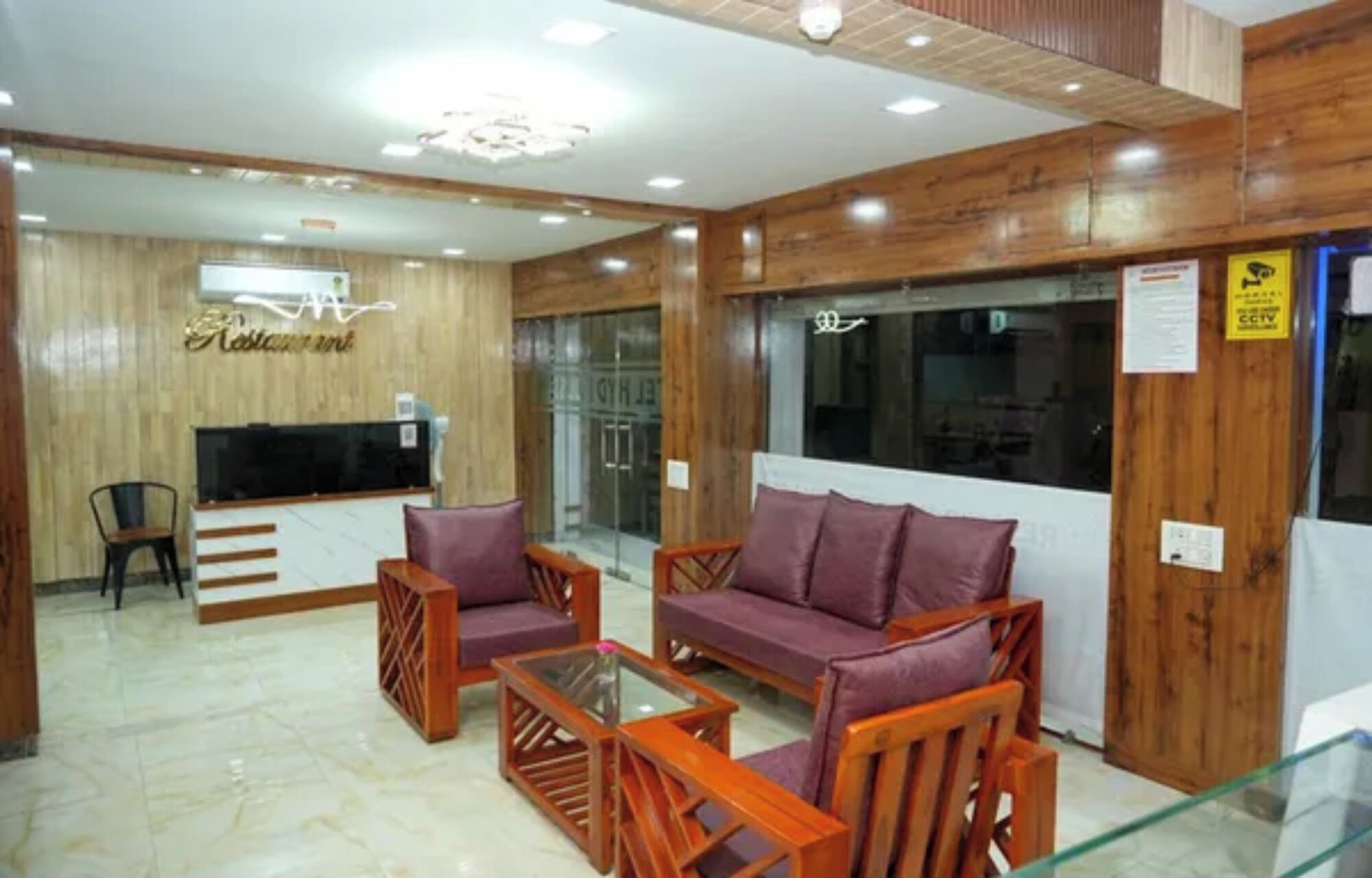 A lobby with a reception desk, a television, seating area with sofas and chairs, and a wooden wall.