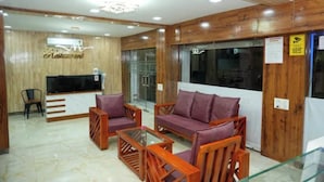 A lobby with a reception desk, a television, seating area with sofas and chairs, and a wooden wall.