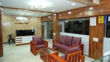 A lobby with a reception desk, a television, seating area with sofas and chairs, and a wooden wall.