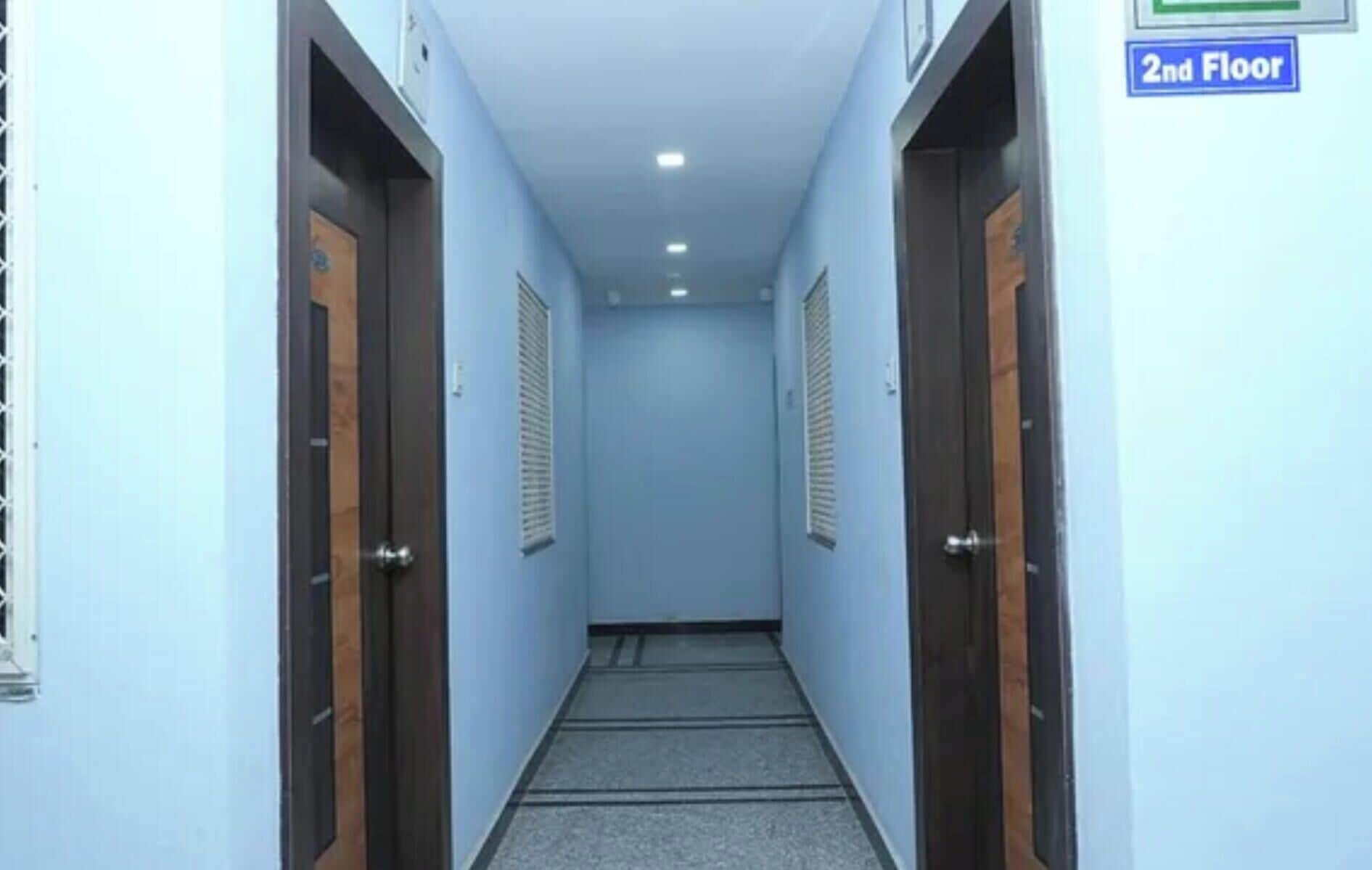 A corridor with doors on both sides, a tiled floor, and a sign indicating the second floor.