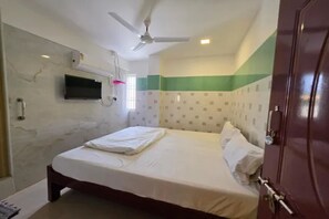 A hotel room with a bed, a ceiling fan, a mounted TV, and a door with a handle. - Fabhotel Ar Residency Ii (Tiruvannamalai)
