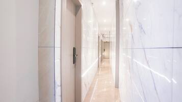A corridor with marble walls and a tiled floor, leading to a door with a handle.