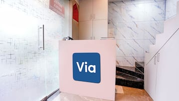 A reception desk with a 'Via' logo, a tiled wall with a geometric pattern, and a marble floor.