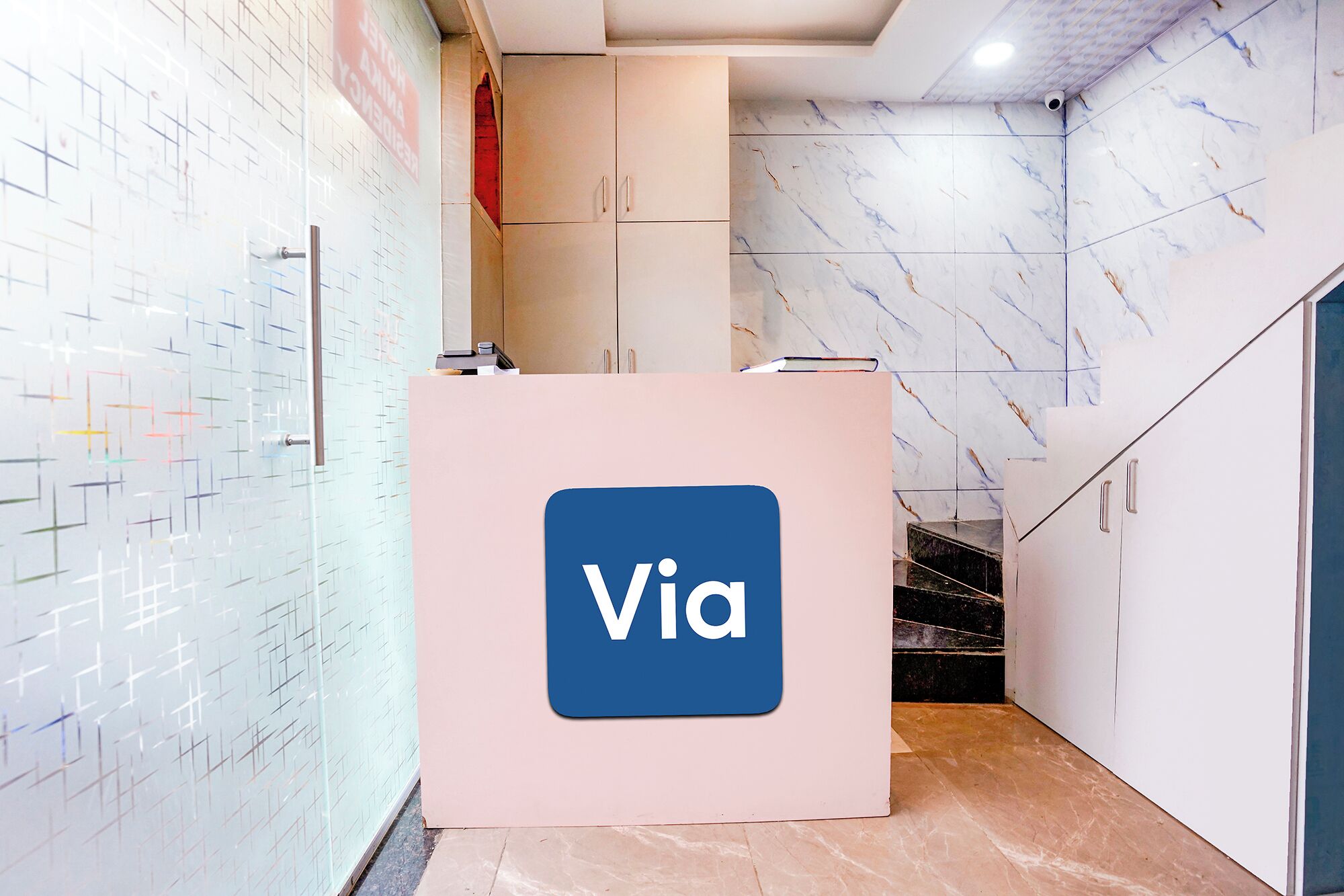 A reception desk with a 'Via' sign, a tiled wall with a geometric pattern, and a marble-patterned wall.
