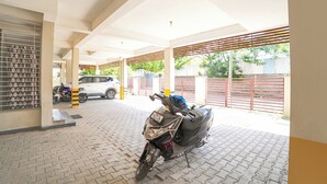 A covered parking area with a motorcycle and a car parked.