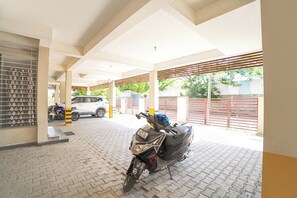 Un área de estacionamiento techada con una motocicleta y un automóvil aparcados.