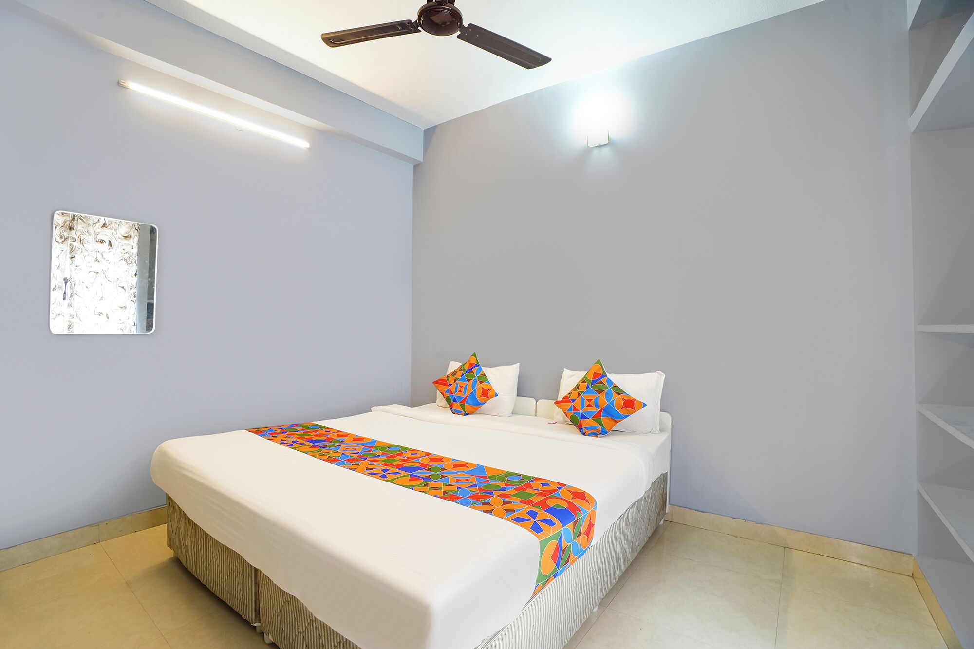 A bedroom with a bed, a ceiling fan, and a wall-mounted light fixture.