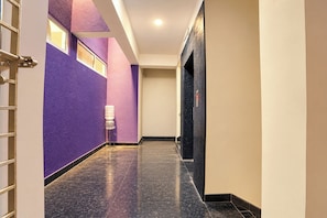 Un pasillo con dispensador de agua, una puerta y una pared con textura.